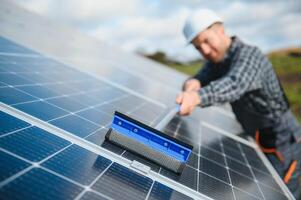Worker cleaning solar panels after installation outdoors photo