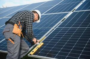 Professional worker installing solar panels on the metal construction, using different equipment, wearing helmet. Innovative solution for energy solving. Use renewable resources. Green energy. photo