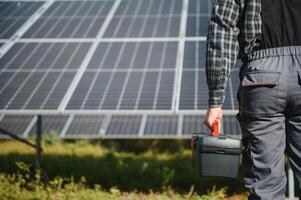 Professional worker installing solar panels on the metal construction, using different equipment, wearing helmet. Innovative solution for energy solving. Use renewable resources. Green energy. photo