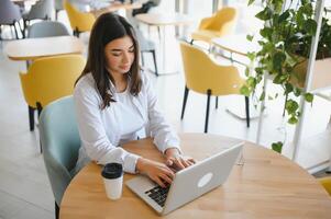 Smiling girl student study online with skype teacher, happy young woman learn language listen lecture watch webinar write notes look at laptop sit in cafe, distant education photo