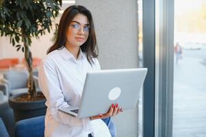 Smiling girl student study online with skype teacher, happy young woman learn language listen lecture watch webinar write notes look at laptop sit in cafe, distant education photo