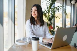 Smiling girl student study online with skype teacher, happy young woman learn language listen lecture watch webinar write notes look at laptop sit in cafe, distant education photo
