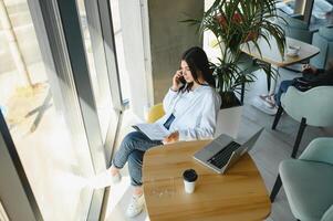 Smiling girl student study online with skype teacher, happy young woman learn language listen lecture watch webinar write notes look at laptop sit in cafe, distant education photo