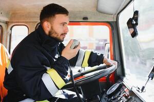 Firefighter using portable radio set in fire truck, space for text photo