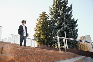 Happy handsome university, college student or young smart successful guy, school pupil with books textbooks smiling outdoors at sunset. Copy space photo