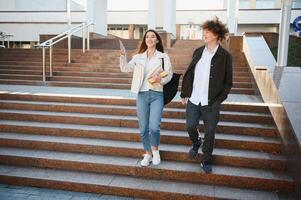 Front view of two students walking and talking in an university campus. photo