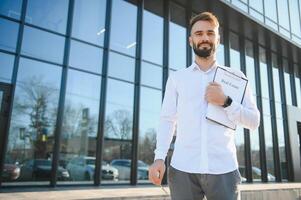 Businessman or real estate agent ready to discuss business and stands against new building photo