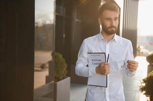 Businessman or real estate agent ready to discuss business and stands against new building photo