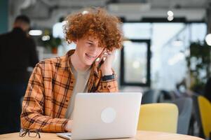 Cheerful male freelancer browsing funny content while networking in social media using netbook technology in street cafe, happy hipster guy enjoying free time for online blogging via laptop photo