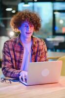 Portrait of Caucasian male freelancer in trendy apparel sitting at cafeteria table and doing remote work for programming design of public website, skilled software developer posing in coworking space. photo