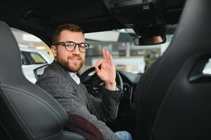 Visiting car dealership. Handsome bearded man is stroking his new car and smiling photo