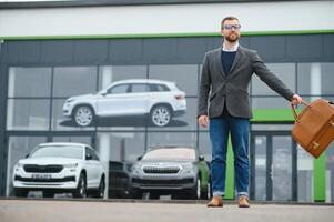 Happy buyer near the car in front of the modern avtosalon building photo