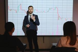Man is standing near projector and showing graphs and business graphs. photo