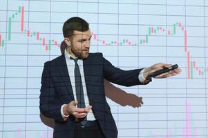 Man is standing near projector and showing graphs and business graphs. photo
