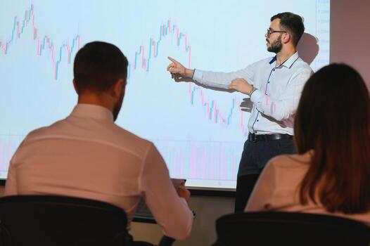 Man is standing near projector and showing graphs and business graphs. photo
