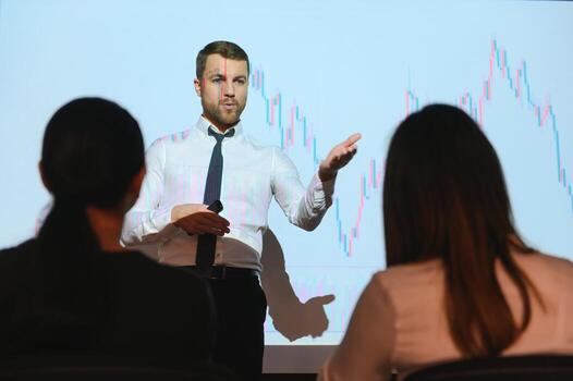 Man is standing near projector and showing graphs and business graphs. photo