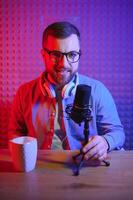 A blogger records content in his studio. The host of the blog is a young man who is very enthusiastic about telling his subscribers a story. photo