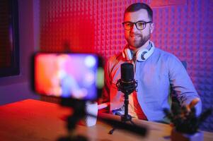 Young man recording or streaming podcast using microphone at his small broadcast studio. Content creator. photo