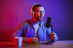 Young man recording or streaming podcast using microphone at his small broadcast studio. Content creator. photo