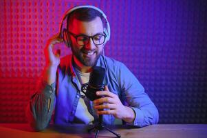 vlogger using smartphone to film podcast in studio. blogger with mobile phone, microphone and headphones filming for social media broadcasting career. photo