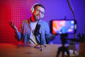 vlogger using smartphone to film podcast in studio. blogger with mobile phone, microphone and headphones filming for social media broadcasting career. photo