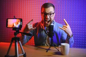 vlogger using smartphone to film podcast in studio. blogger with mobile phone, microphone and headphones filming for social media broadcasting career. photo