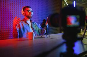 Young man recording or streaming podcast using microphone at his small broadcast studio. Content creator. photo