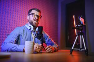 vlogger using smartphone to film podcast in studio. blogger with mobile phone, microphone and headphones filming for social media broadcasting career. photo
