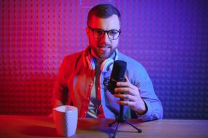 Young man recording or streaming podcast using microphone at his small broadcast studio. Content creator. photo