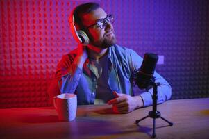 Young man recording or streaming podcast using microphone at his small broadcast studio. Content creator. photo