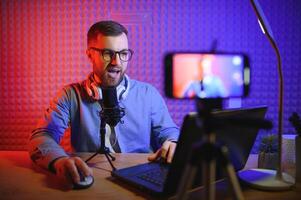 Young man recording or streaming podcast using microphone at his small broadcast studio. Content creator. photo
