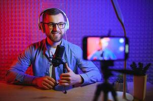 Young man recording or streaming podcast using microphone at his small broadcast studio. Content creator. photo