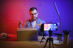 Young man recording or streaming podcast using microphone at his small broadcast studio. Content creator. photo