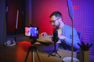 Joyful young man recording unboxing in studio photo