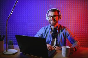 Young man recording or streaming podcast using microphone at his small broadcast studio. Content creator. photo
