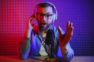 vlogger using smartphone to film podcast in studio. blogger with mobile phone, microphone and headphones filming for social media broadcasting career. photo