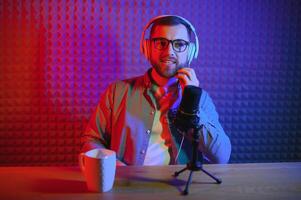 vlogger using smartphone to film podcast in studio. blogger with mobile phone, microphone and headphones filming for social media broadcasting career. photo