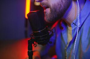 Young man recording or streaming podcast using microphone at his small broadcast studio. Content creator. photo