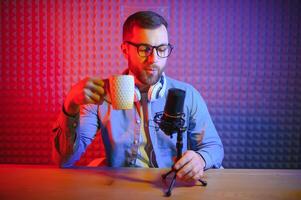 Young man recording or streaming podcast using microphone at his small broadcast studio. Content creator. photo