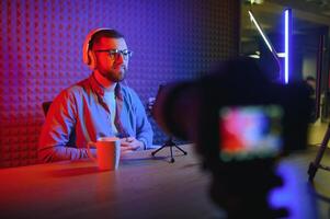 Young man recording or streaming podcast using microphone at his small broadcast studio. Content creator. photo