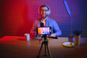 Young man recording or streaming podcast using microphone at his small broadcast studio. Content creator. photo