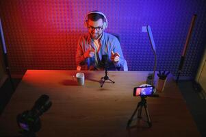 vlogger using smartphone to film podcast in studio. blogger with mobile phone, microphone and headphones filming for social media broadcasting career. photo