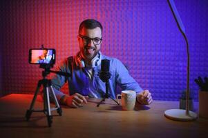 vlogger using smartphone to film podcast in studio. blogger with mobile phone, microphone and headphones filming for social media broadcasting career. photo