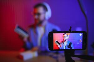Young man recording or streaming podcast using microphone at his small broadcast studio. Content creator. photo