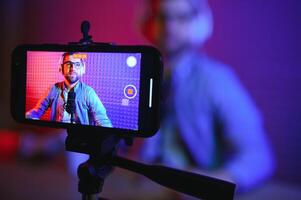 vlogger using smartphone to film podcast in studio. blogger with mobile phone, microphone and headphones filming for social media broadcasting career. photo