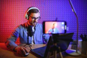 vlogger using smartphone to film podcast in studio. blogger with mobile phone, microphone and headphones filming for social media broadcasting career. photo