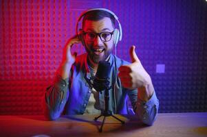 Young man recording or streaming podcast using microphone at his small broadcast studio. Content creator. photo