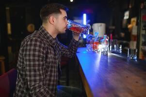 Handsome bearded man drinking beer at the bar counter in pub photo