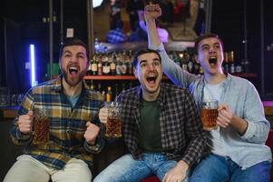Soccer fans at the bar. Happy football fans cheering at bar and drinking beer while bartender serving beer at the background photo
