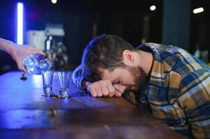 triste joven hombre sentado a bar mostrador en pub. trastornado hombre bebidas alcohol porque de problemas a trabajar. foto